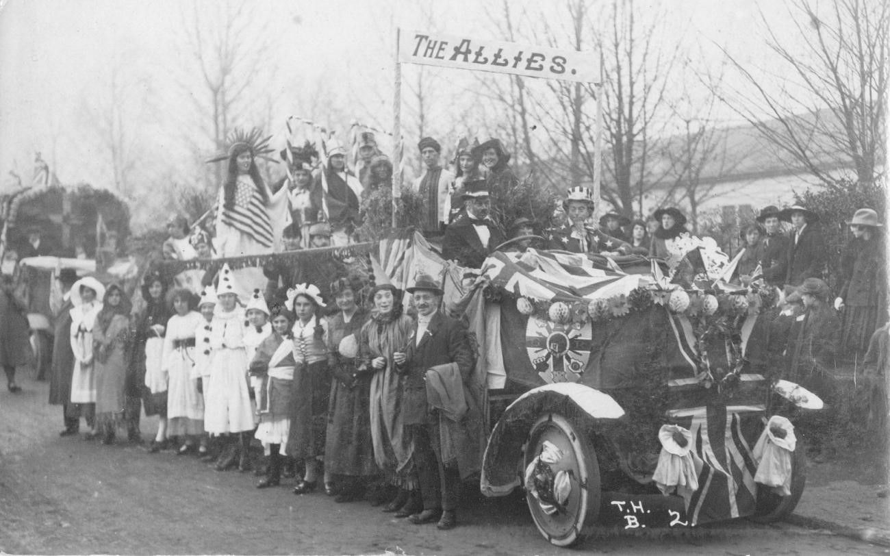 A group of people standing around a car with a flag on it

Description automatically generated with low confidence