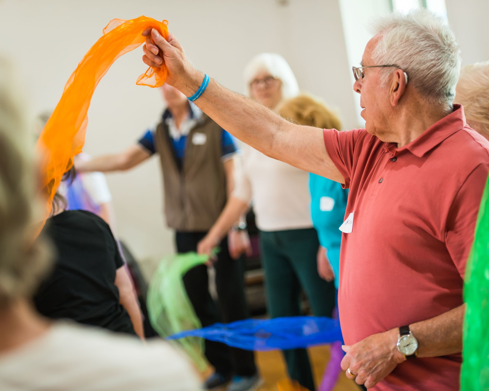 An elderly man waving an orange coloured cloth in the air