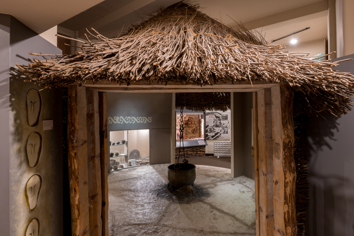 View inside a recreation of a historic hut with a roof made of branches